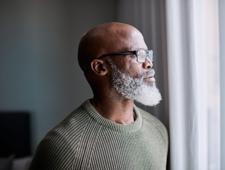 image of African American male with gray beard looking out window